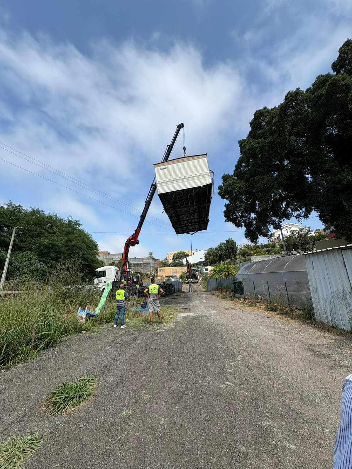 Mobile home being lifted by crane over street